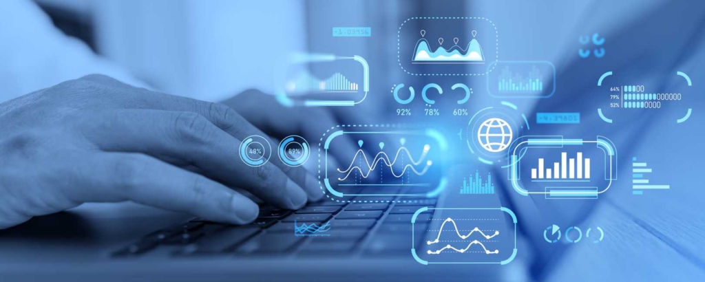 Compliance-Driven Patch Updates. Close-up of a person's hands typing on a laptop keyboard. Bright blue futuristic graphics — including graphs, pie charts, world maps, and percentages — float around the hands, suggesting data analytics, financial modeling, or business intelligence work happening in real time.
